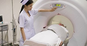Middle aged man lying on the CT scanner during machine imaging his body, lights up infrared rays and male patient passes through the circle.