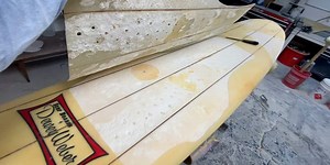 A Dewey Weber surfboard is fixed by filling dings and water proofing