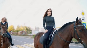 Two beautiful girls riding a horse on the asphalt road.