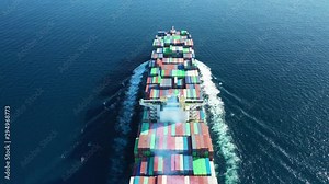 Aerial drone tracking video of Container cargo Ship carrying load in truck-size colourful containers cruising the deep blue Pacific ocean