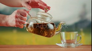 Pouring fresh tea in glass cup close-up. Freshly brewed tea ceremony process, healthy morning, detox hot drink.