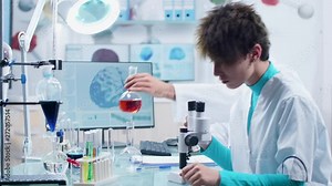 Two scientists in high end secure laboratory working with different colored samples in tubes. In the background - a computer monitor is displaying a 3D brain simulation