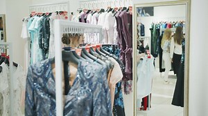Woman holds up shirt in shopping mall mirror - Free Stock Video