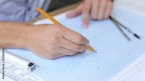 The engineer builder works on a graph paper with a ruler and a compass