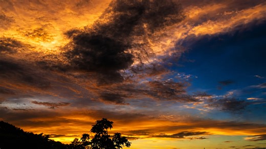 Golden hour sky with dramatic cloud formations and silhouettes below