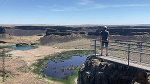 A man takes in the scenery of beautiful Dry Falls State Park canyon and lakes from a viewpoint. Taken in summer - Nr Coulee City, Washington, USA