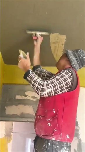 Worker applying smooth plaster finish to the interior ceiling surface