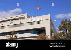 Modern architecture of the Canadian Embassy on Pennsylvania Avenue in Washington D.C. The Canadian flag flies high above the building, with smaller flags lining the exterior Stock Video Footage - Alamy