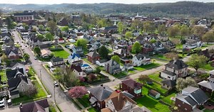 Appalachian Mountains, small community in coal mining town. Rising aerial reveal of homes in spring season. Rural Appalachia.