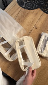 A woman is unboxing and reviewing a set of cosmetic bags. The cosmetic bags are of different sizes. She takes them out of the packaging. Vertical video. Point of view