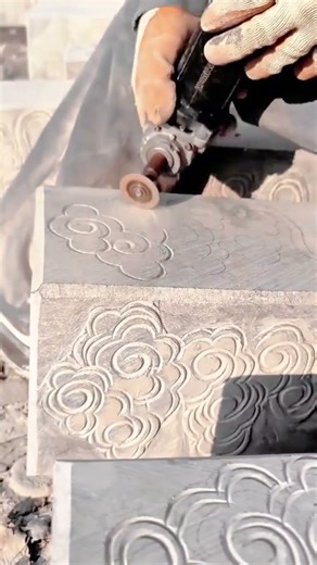 A worker is engraving a stone block with a rotary tool