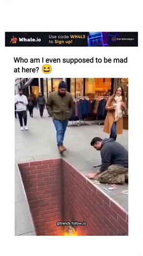 AI Clips • Funny Clips on Instagram: "The post features a 10-second video of a hyper-realistic 3D street art installation in New York City, depicting a brick-lined hole with glowing lantern-lit stairs, which tricks pedestrians into dramatic reactions, including a man comically stumbling as if falling in. Captioned with bemused humour, it captures the poster's amusement at the illusion's chaos, questioning blame amid the light-hearted pranks on unsuspecting walkers. Replies mix awe at the artwork