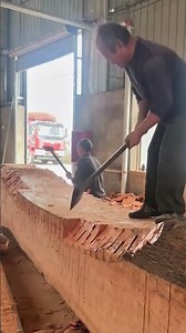 Carving a large wooden beam manually using an adze to shape and smooth the surface
