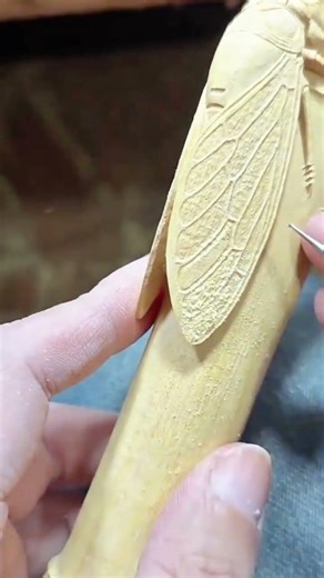 carving and detailing the wings of wooden insect sculpture