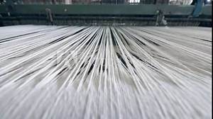 Industrial textile factory. Close up of thick white threads moving through the loom