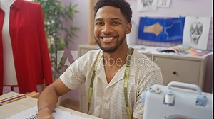 Smiling african man at tailoring shop with measuring tape, sewing machine, and fashion design sketches