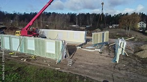 Modular home assembly on construction site with crane