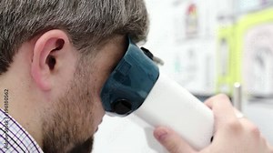 Man looks in apparatus for the treatment of spasm of accommodation, amblyopia and binocular vision disorders. Patient in ophthalmology clinic