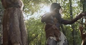 At sunlight tribe of cavemen neanderthals wearing animal skin holding weapon dancing having fun in prehistoric forest ancient bushman aboriginal evolution stone primitive cave slow motion