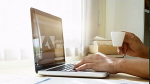 Cinemagraph of steaming coffee on desk of man who using computer laptop.