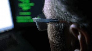 A software developer writing code in close-up. Hacker, cyber security, penetration testing concept. Screen light and computer code reflecting on his face. System administrator. 4K Resolution.