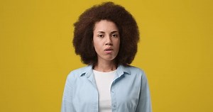 clip-1102787721-young-african-woman-standing-over-yellow-studio