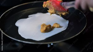 Closeup of making steaming hot crepe layer on a cast iron pan. A thin pancake made with rice flour dough and condensed milk stuffing. Thin batter being spread and cooked for making 'Pithe' and 'dosa'