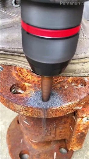 Drilling and enlarging a hole on a rusty metal pipe flange using a sharp step drill bit