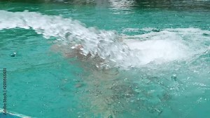Teenager girl in swimsuit swims in pool with water jets