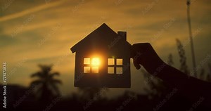 Dream buy house. Real estate insurance. Paper house hands family, sun shines in window close-up. Hands, paper house at sunset. Symbol home, family comfort, happy. Concept building house family, child.