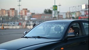 A young man arrived at the parking lot and climbs out of the car through the window. Old car and door handle problems