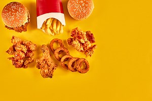 Top view hamburger, french fries and fried chicken on yellow...