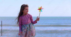 Beautiful young girl and rotating color pinwheel on the beach