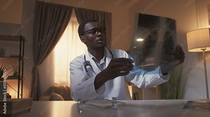 Lung diagnostic. Radiology examination. Covid-19 pneumonia. Concerned male doctor studying chest X-ray working from home at modern interior.