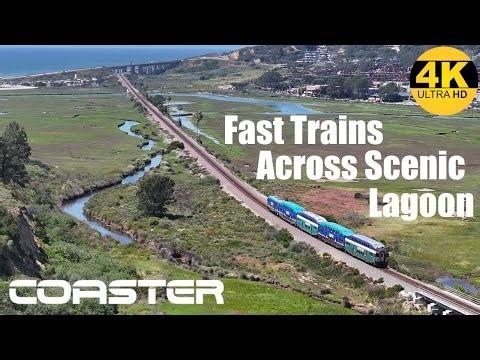 Coaster Commuter Trains Racing Across Coastal Marsh - 4K HD Drone Video