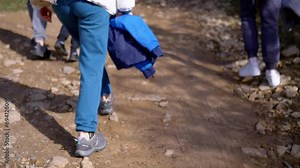 Group of Tourists Climb up a Forest Path into Mountains. Back view. Close-up. Legs, steps. Body part. Hiking in Carpathian Mountains. Unrecognizable people. Walking with family in wild nature. Blur.