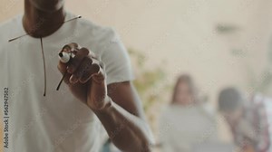 Black man writes word teamwork on glass with a marker, against the background of office workers. Word teamwork written on glass, the concept of command work