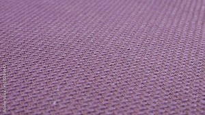 Relief, textured textile background made of purple color mauve shade cotton fabric on a rotating display case. Sewing, fashion and clothing design. Close-up view.