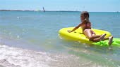 Adorable girl swim on inflatable air mattress in the sea