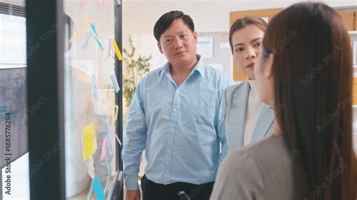 Creative Asian professionals connecting diverse business ideas on a brainstorming wall. A collaborative team working together to develop innovative solutions and strategic growth in a modern office