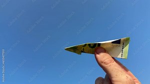 Euro note as paper airplane. 100 euros Banknote in form of paper plane. Money of European Union Euro note in hand on blue sky background. Concept of economy and banking. Euro Fall or rise of currency