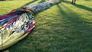 Hot air balloon textiles laying on a green grass. European balloon festival in Spain. International meeting of hot air balloons and flying competition.