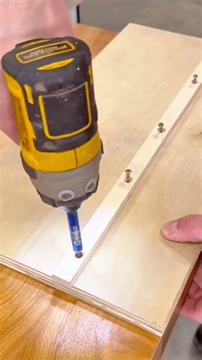 drilling screws into wooden board using electric impact driver for assembling furniture project