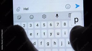 A person writes a close-up letter on a smartphone HELP ME. He types with his fingers on the touch keyboard in the dark, lighting up from the screen.