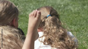 Children relaxing on green grass in the backyard. Close-up of children's bare feet outside. Little girls barefoot lying on the lawn on a warm summer day.
