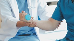 Download Doctor or Physiotherapist working examining treating injured arm of athlete male patient, stretching and exercise, Doing the Rehabilitation therapy pain in clinic. for free