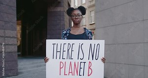 Portrait of african american activist holding placard with there is no planet b at city street. Young woman supporting ecology and clean planet movement. Concept of save Earth