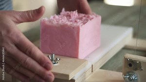 A woman master soap maker cuts handmade lavender soap on a wooden string cutter. Home production of natural cosmetics
