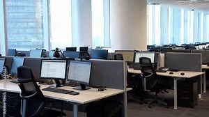 Side view of an open office space with rows of computer desks, positioned near panoramic windows, offering a bright, spacious environment.