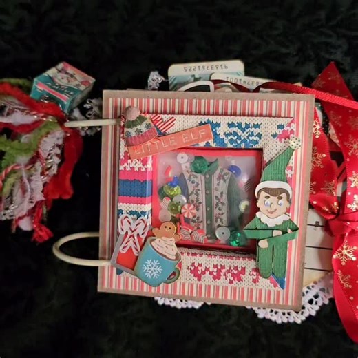 Lynn QV on Instagram: "I have a bunch of chipboard, pre-cut journal sets I'm using up. It's not my first choice but I got the lot at a great price, so chipboard it is. I recently learned how to make a shadow box (this one measures 3" on the outside and 2" inside). Thank you CraftyTinas on YT for your videos. I placed a shaker in the sb for my cover. Along with some lovely fibres an adorable charm was made with a miniaturized Snowy Os Cereal box. Printables are from @kbandfriends - I used images